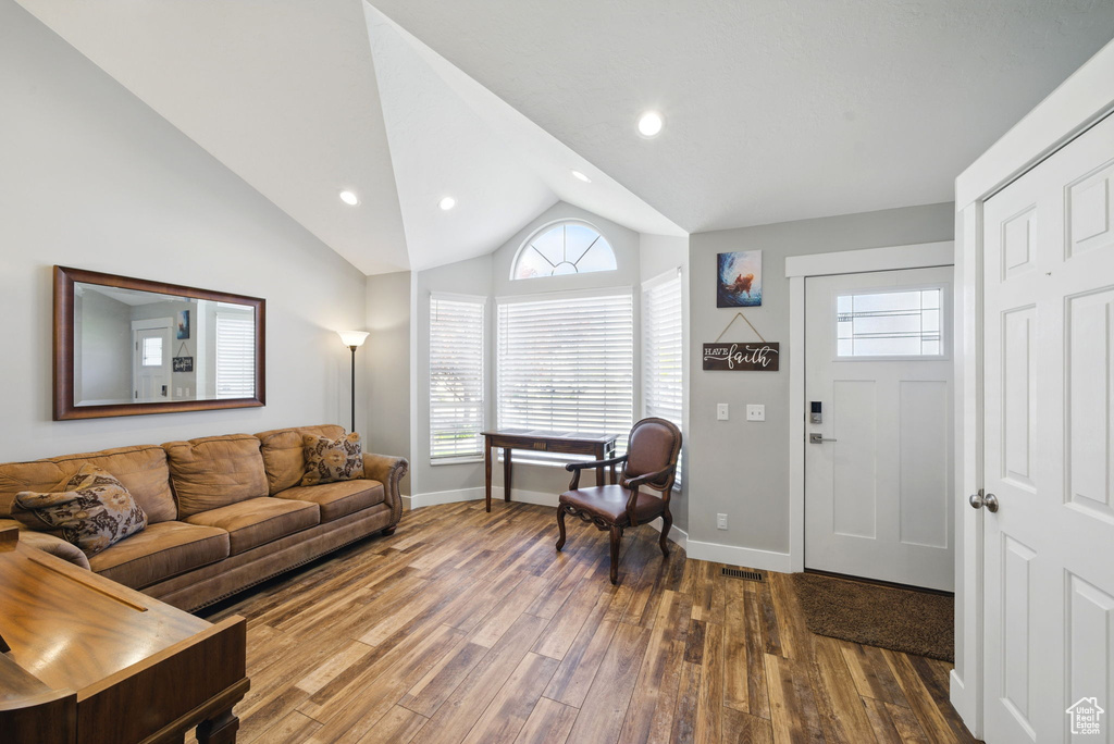 Living room featuring baseboards, lofted ceiling, wood finished floors, and a wealth of natural light