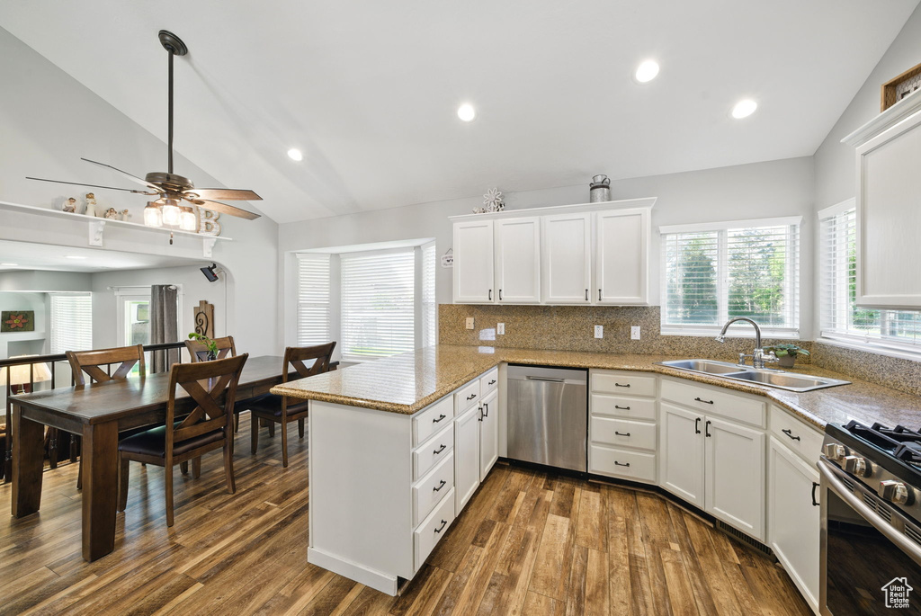 Kitchen with a peninsula, appliances with stainless steel finishes, a sink, and vaulted ceiling