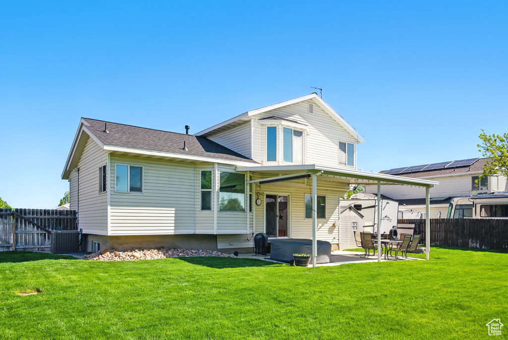 Back of property featuring a lawn, a hot tub, a fenced backyard, and a patio area
