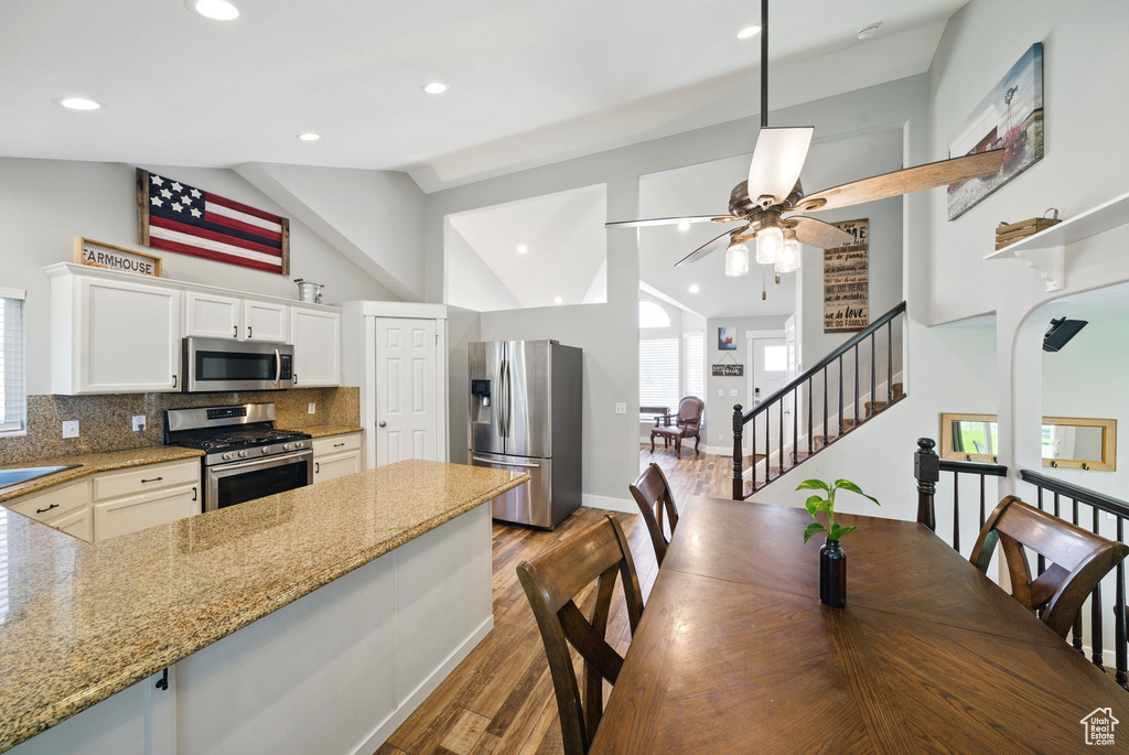 Kitchen with lofted ceiling, white cabinetry, a ceiling fan, light wood-style flooring, and stainless steel appliances
