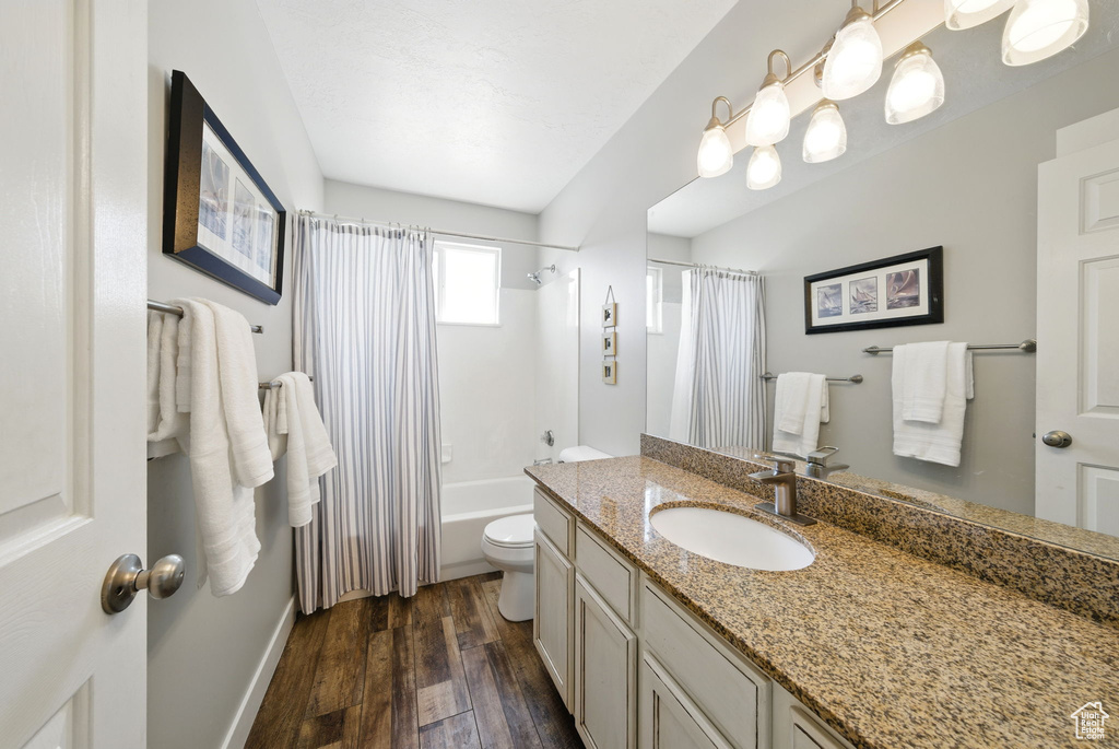 Bathroom with vanity, toilet, shower / bath combo with shower curtain, baseboards, and wood finished floors