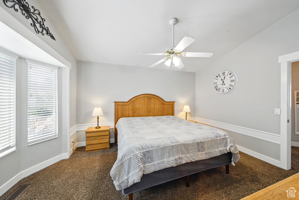 Bedroom featuring baseboards, lofted ceiling, and dark colored carpet