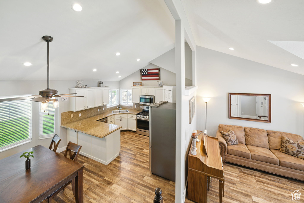 Kitchen featuring ceiling fan, a peninsula, open floor plan, stainless steel appliances, and white cabinetry