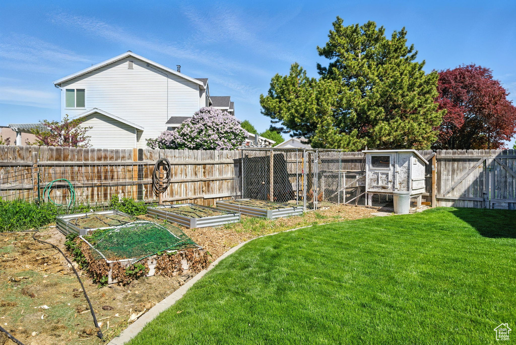 View of yard with an outdoor structure, exterior structure, a fenced backyard, and a vegetable garden
