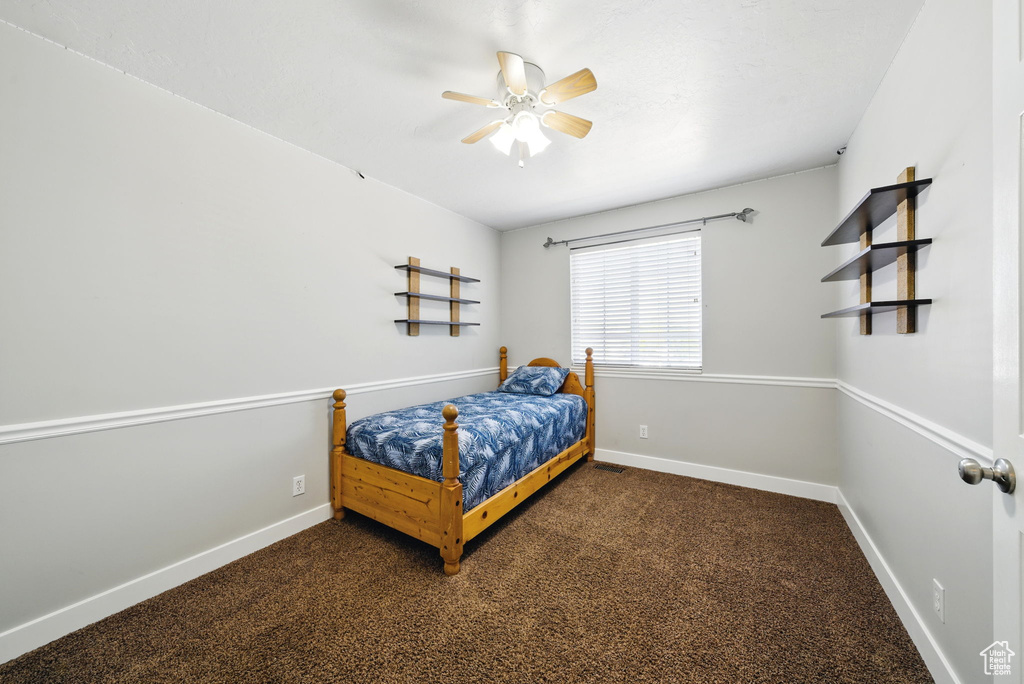 Bedroom featuring baseboards, ceiling fan, and dark colored carpet