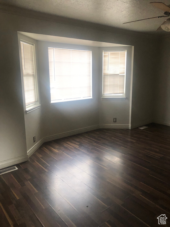 Spare room with dark wood-style flooring, a ceiling fan, a textured ceiling, and visible vents