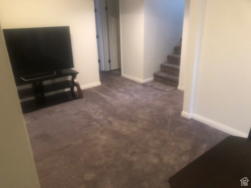 Living room with carpet flooring, baseboards, and stairs