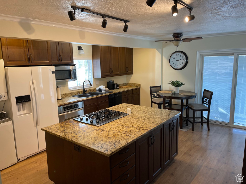 Kitchen featuring a textured ceiling, a sink, track lighting, light wood-style floors, and stainless steel appliances