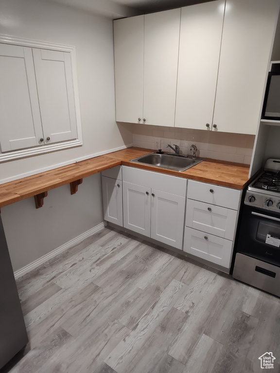 Kitchen featuring a sink, butcher block counters, and gas stove