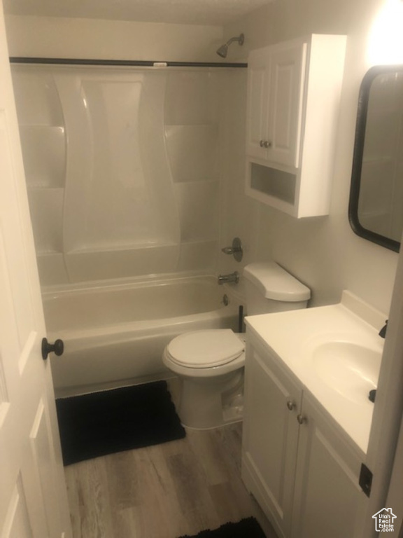 Bathroom featuring vanity, toilet, wood finished floors, and  shower combination