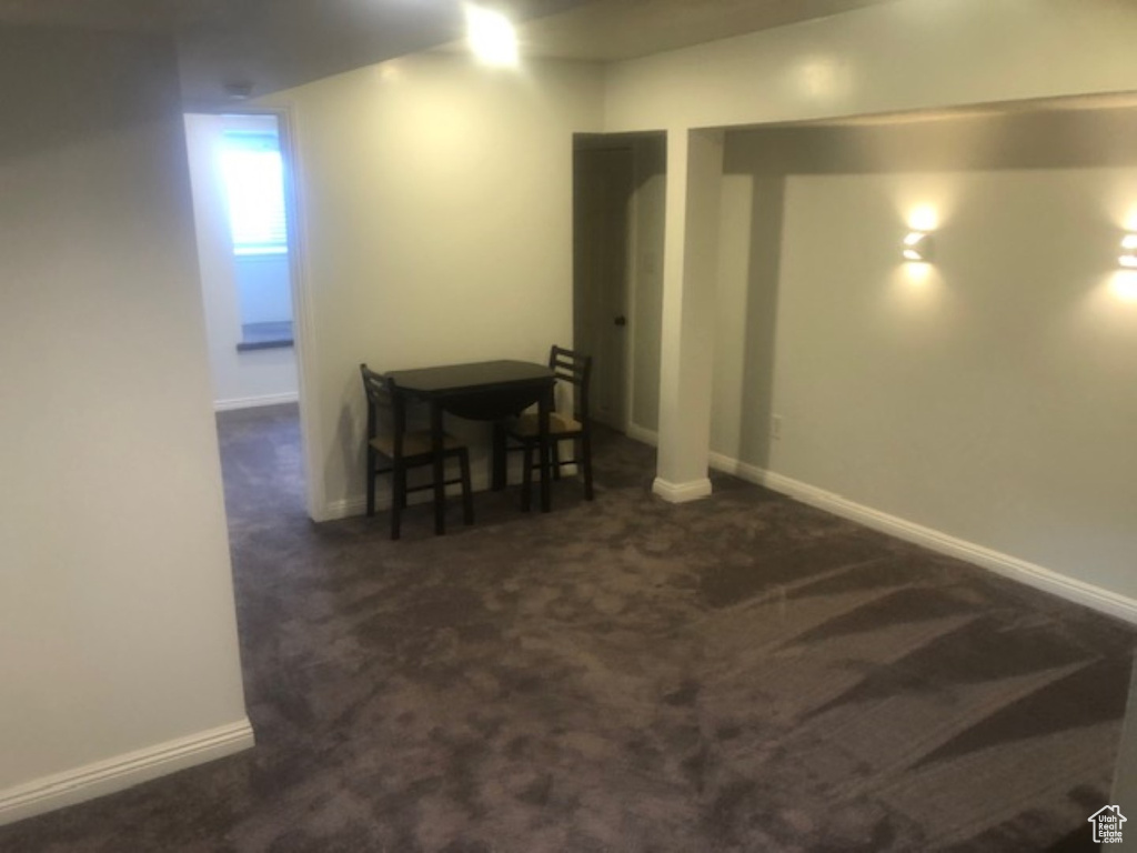 Basement with baseboards and dark colored carpet