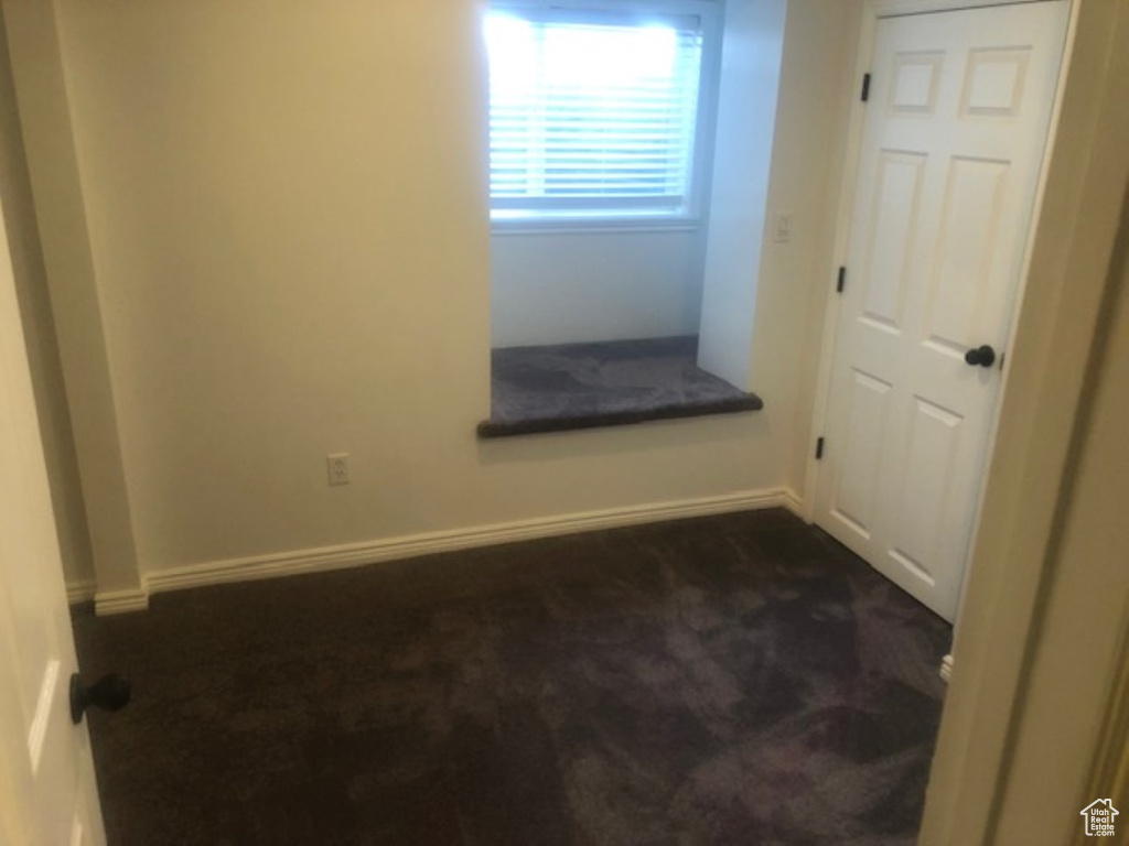 Unfurnished room with baseboards and dark colored carpet