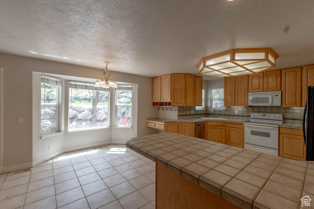 Kitchen featuring plenty of natural light, tile countertops, a sink, and white appliances