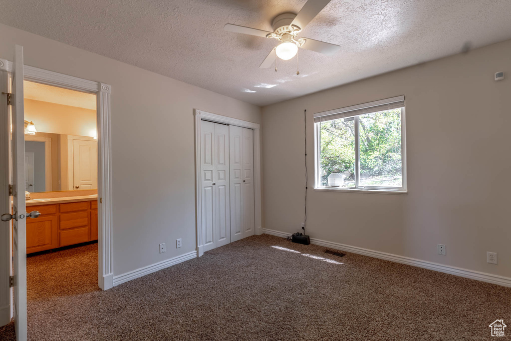Unfurnished bedroom featuring a textured ceiling, visible vents, carpet floors, baseboards, and a closet