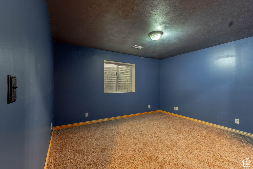 Empty room with carpet floors, baseboards, and visible vents