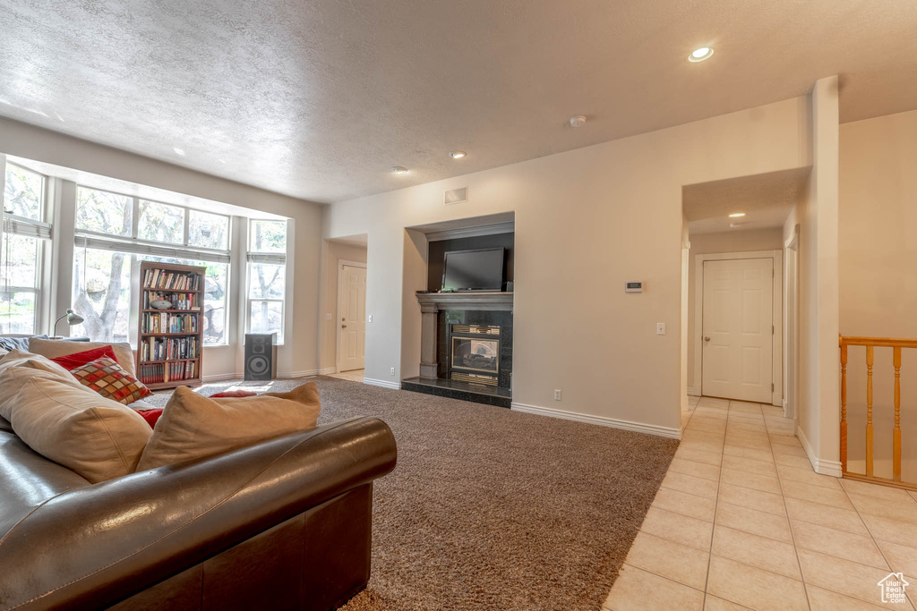 Living room with light colored carpet, recessed lighting, baseboards, light tile patterned floors, and a tile fireplace