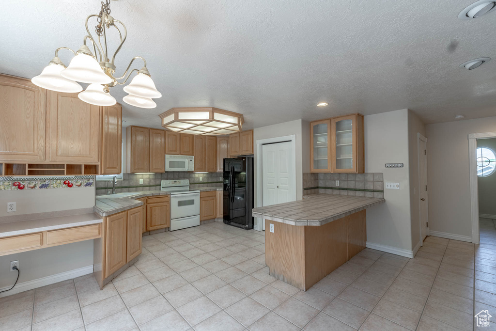 Kitchen featuring white appliances, a peninsula, a sink, and backsplash