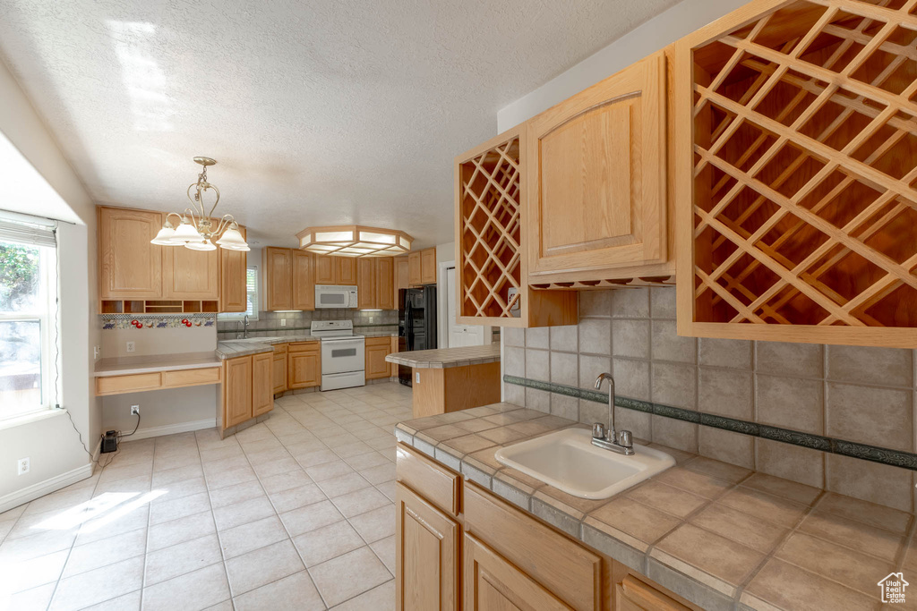 Kitchen featuring a sink, light brown cabinets, tasteful backsplash, and white appliances