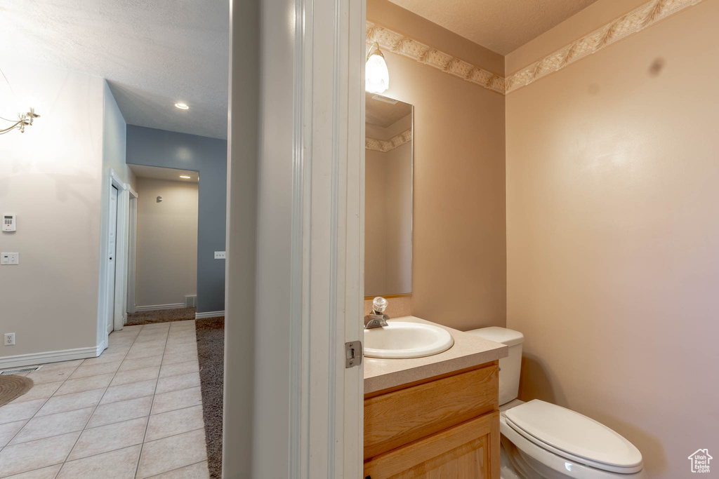 Bathroom with vanity, baseboards, tile patterned flooring, and toilet
