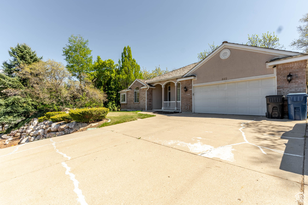 Single story home featuring a garage, stucco siding, concrete driveway, and brick siding