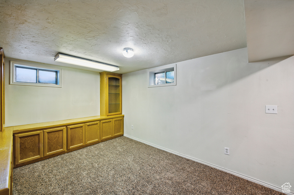 Below grade area with carpet floors, a textured ceiling, and baseboards