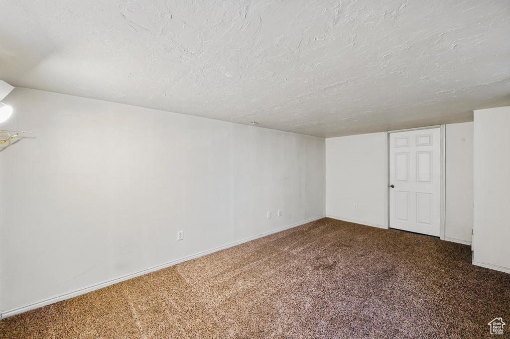 Basement with carpet flooring, a textured ceiling, and baseboards