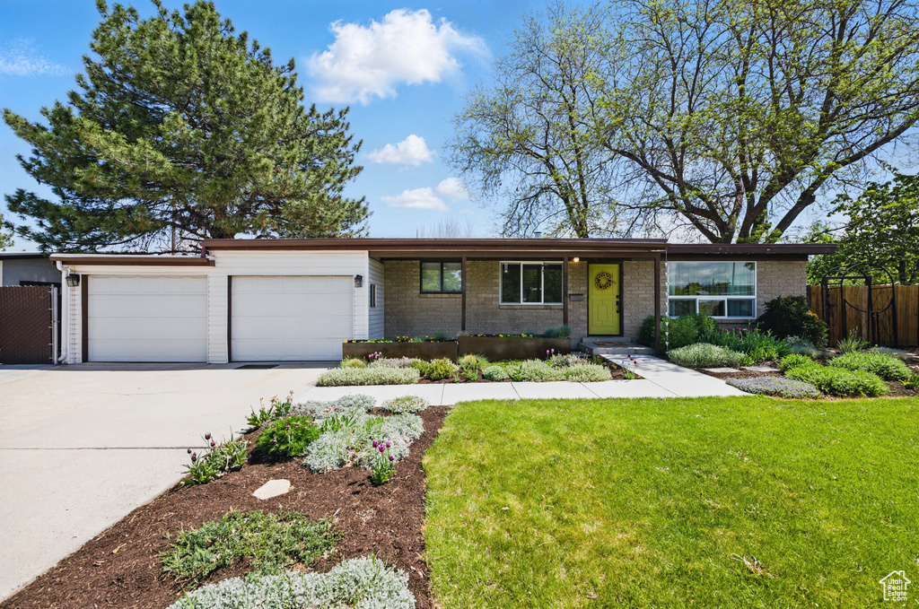Ranch-style home with fence, an attached garage, concrete driveway, and brick siding