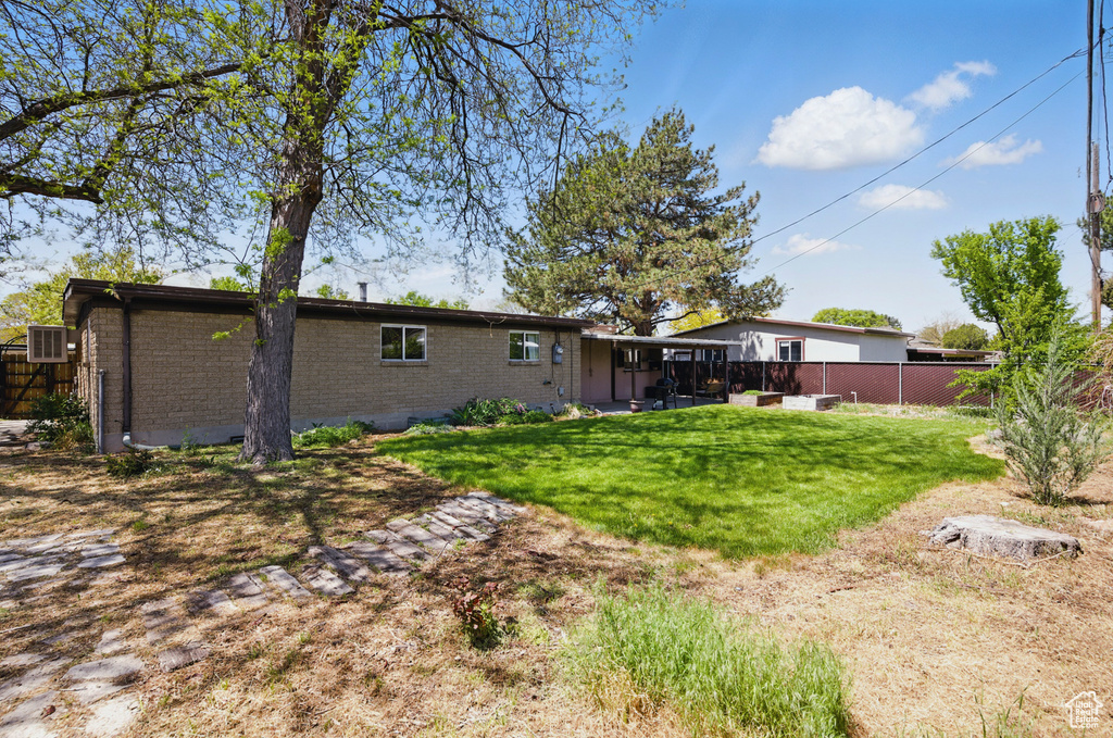 Rear view of house with brick siding, a lawn, fence, and a patio area