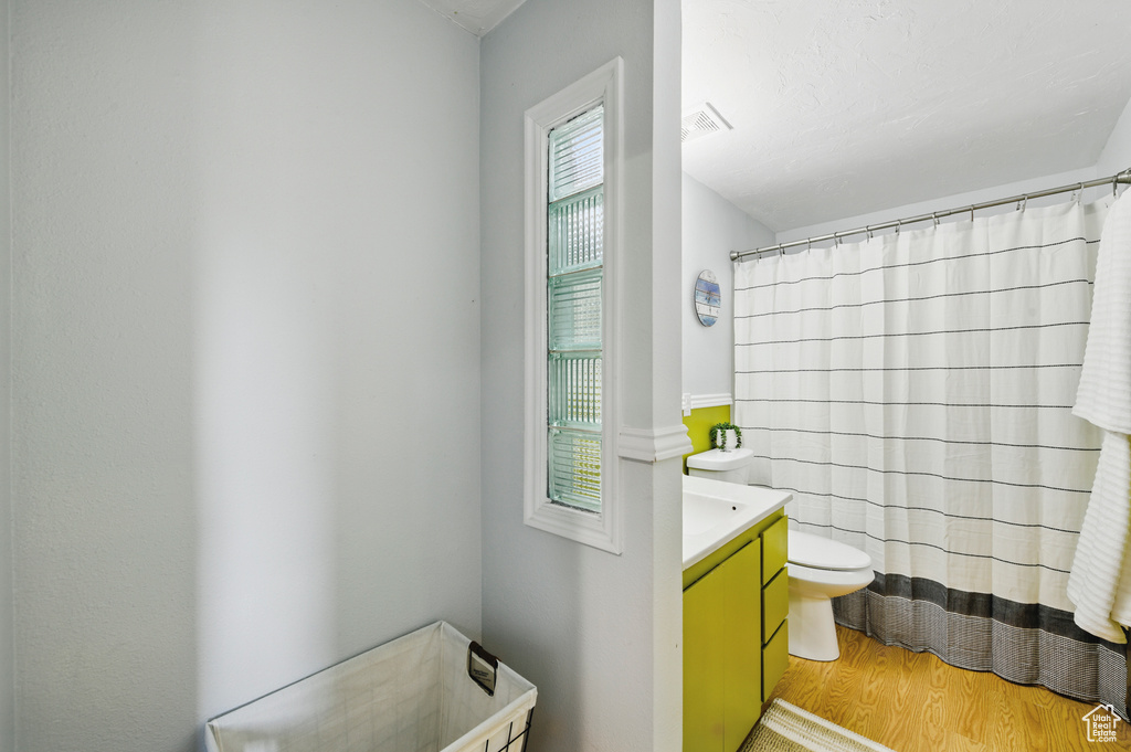 Full bathroom with visible vents, wood finished floors, vanity, toilet, and a shower with shower curtain