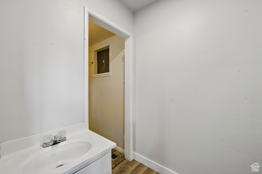 Bathroom featuring baseboards, wood finished floors, and vanity