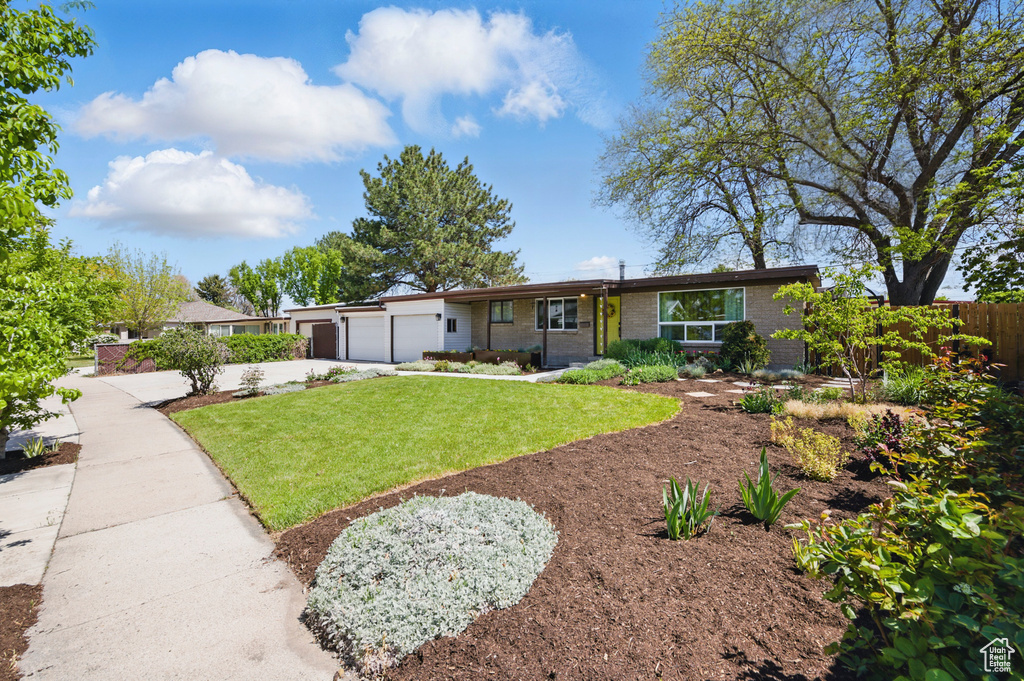 View of front of home featuring a garage, fence, a front yard, brick siding, and concrete driveway