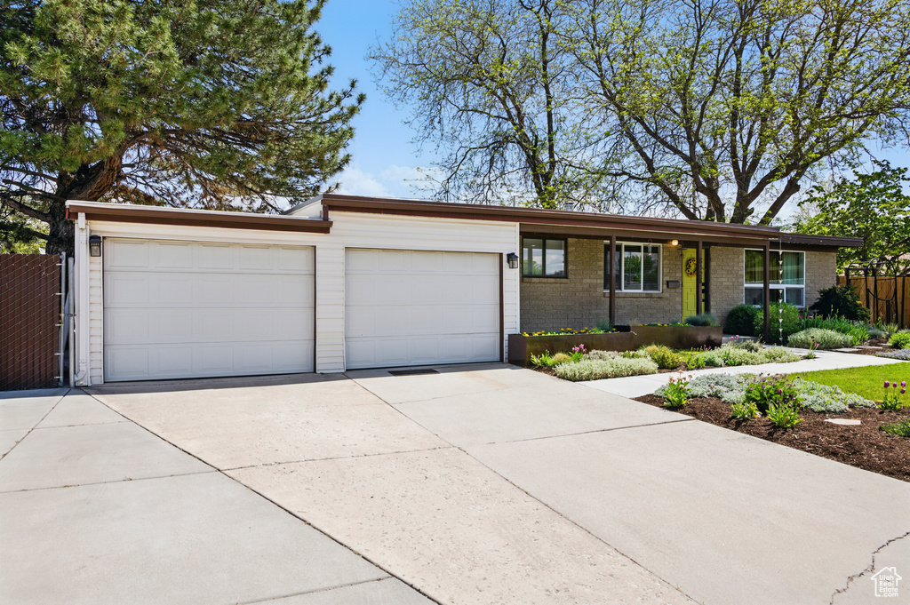 Ranch-style house featuring an attached garage, fence, brick siding, and concrete driveway