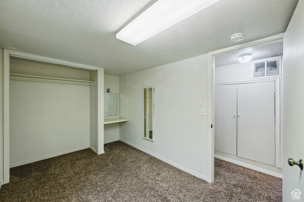 Unfurnished bedroom with carpet floors, baseboards, a textured ceiling, and visible vents