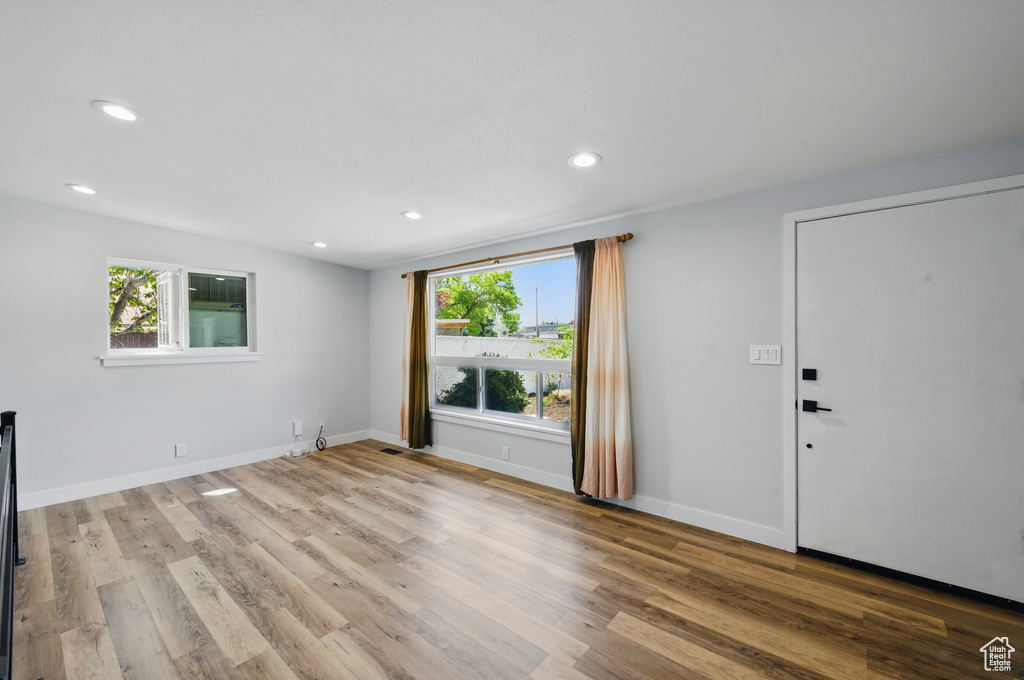 Unfurnished living room featuring recessed lighting, baseboards, plenty of natural light, and wood finished floors