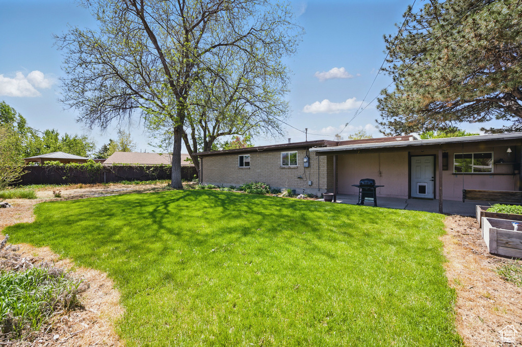 Rear view of house with a lawn, fence, and brick siding