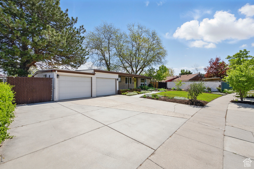 Single story home with an attached garage, fence, and driveway