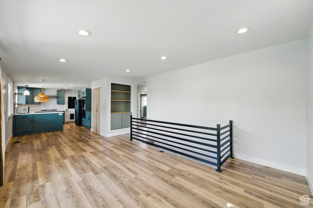 Unfurnished living room with a sink, baseboards, light wood finished floors, and recessed lighting
