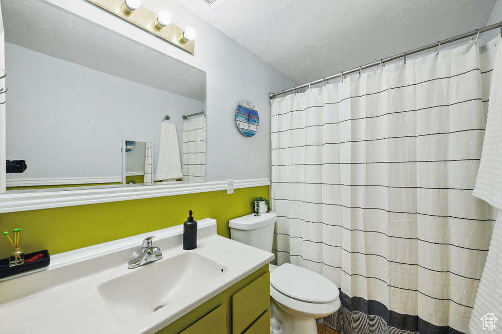 Full bath with vanity, a shower with curtain, and toilet