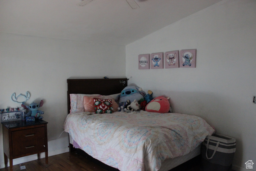 Bedroom featuring baseboards, wood finished floors, and vaulted ceiling