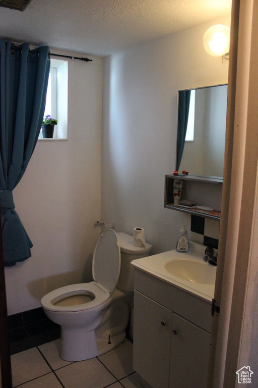 Bathroom featuring vanity, a textured ceiling, tile patterned floors, and toilet