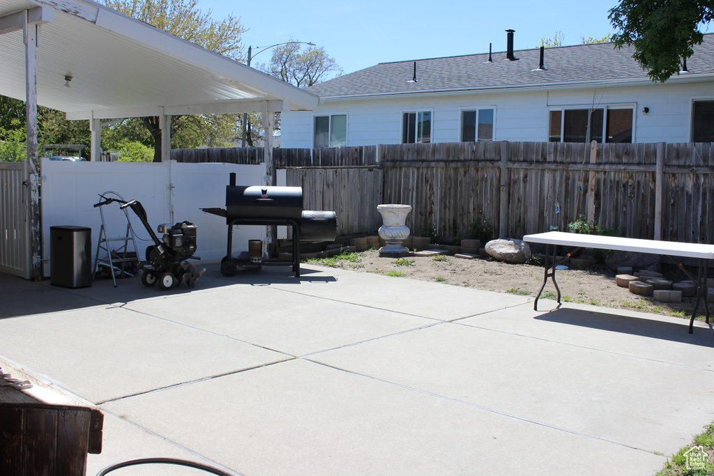 View of patio with fence and a grill