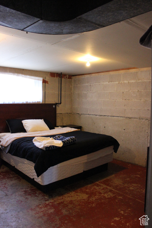 Bedroom with concrete floors and concrete block wall