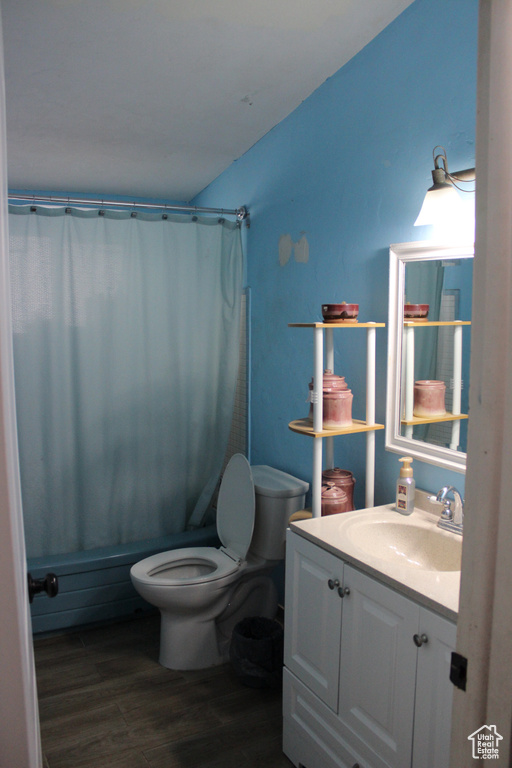 Full bathroom featuring vanity, toilet, wood finished floors, and shower / tub combo with curtain