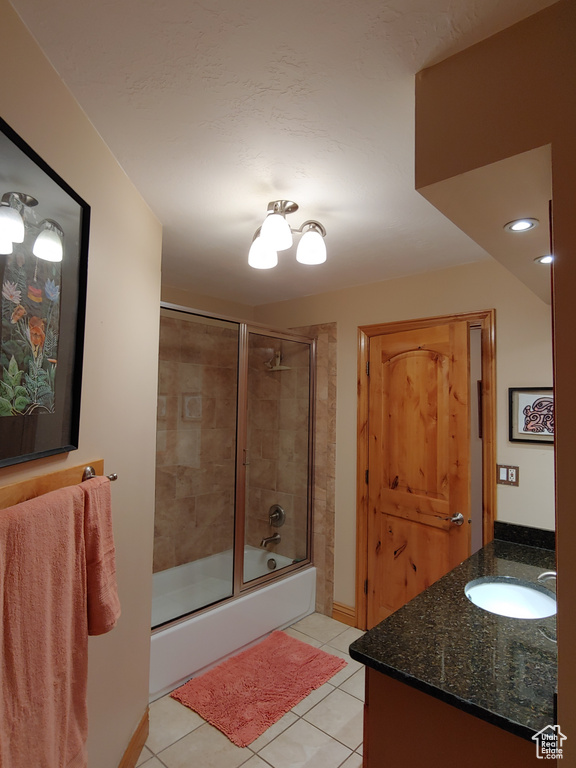 Full bathroom with tile patterned flooring, baseboards, combined bath / shower with glass door, and vanity