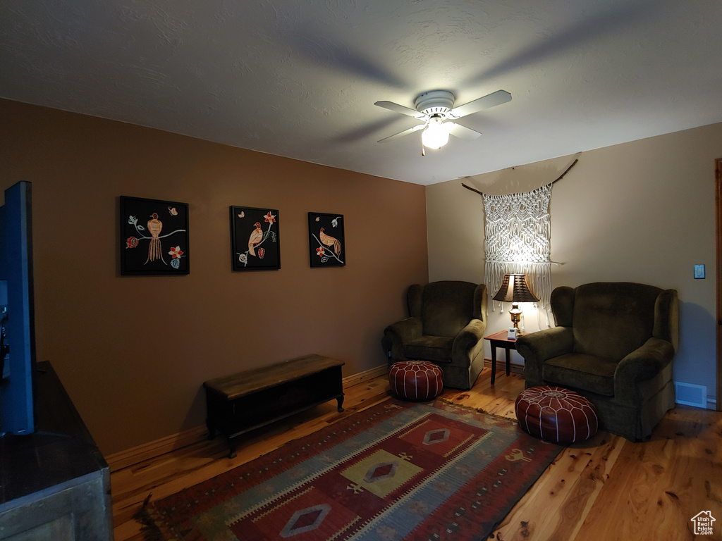 Living room featuring baseboards, a ceiling fan, wood finished floors, and visible vents