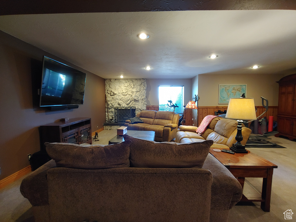 Living room with light carpet, recessed lighting, and a stone fireplace