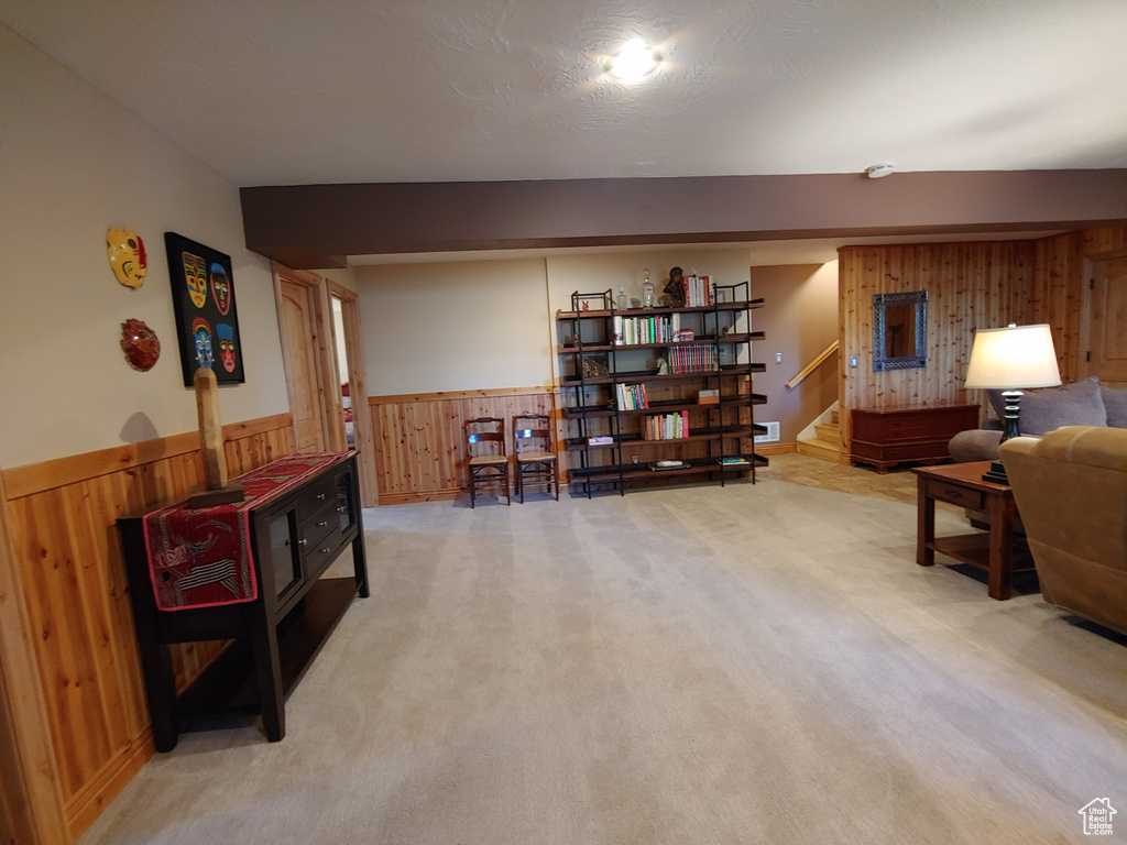 Living area with visible vents, stairs, light carpet, wooden walls, and a wainscoted wall