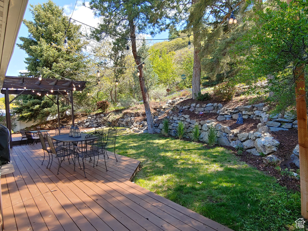Deck with a pergola, outdoor dining area, and a yard