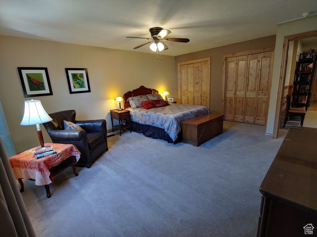 Bedroom with carpet flooring, a ceiling fan, and two closets