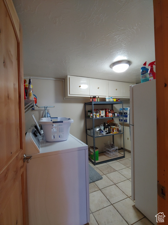 Laundry room featuring independent washer and dryer, light tile patterned flooring, laundry area, and a textured ceiling
